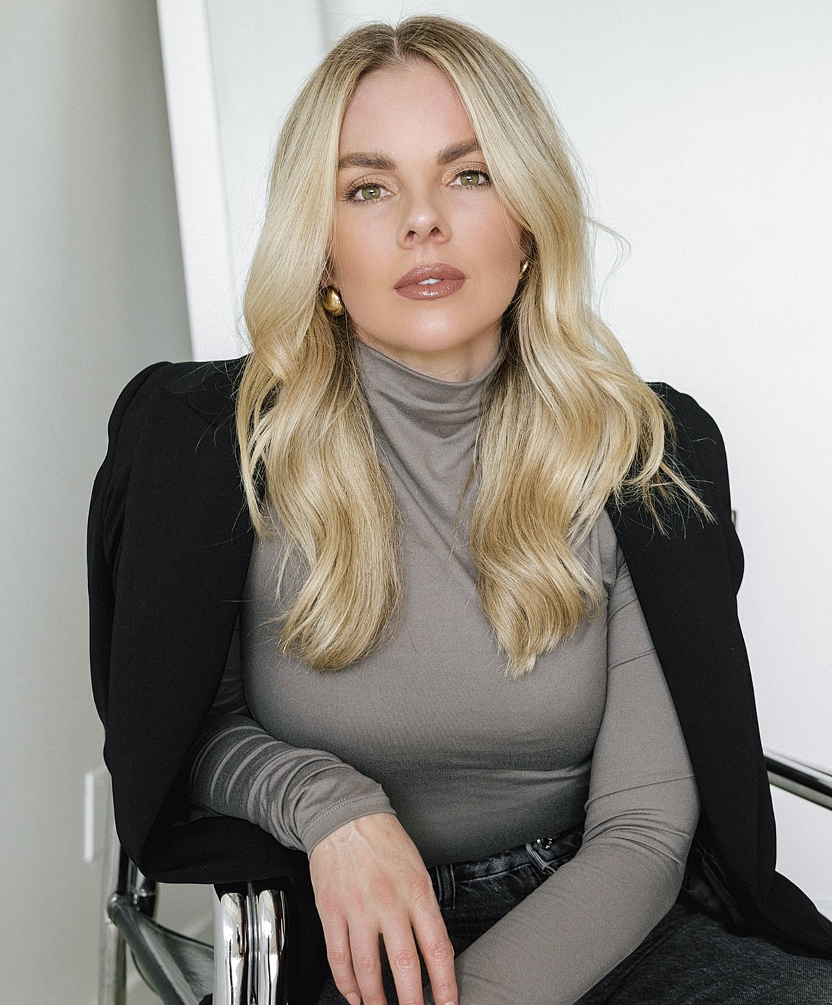 Blonde woman in stylish outfit posing indoors.