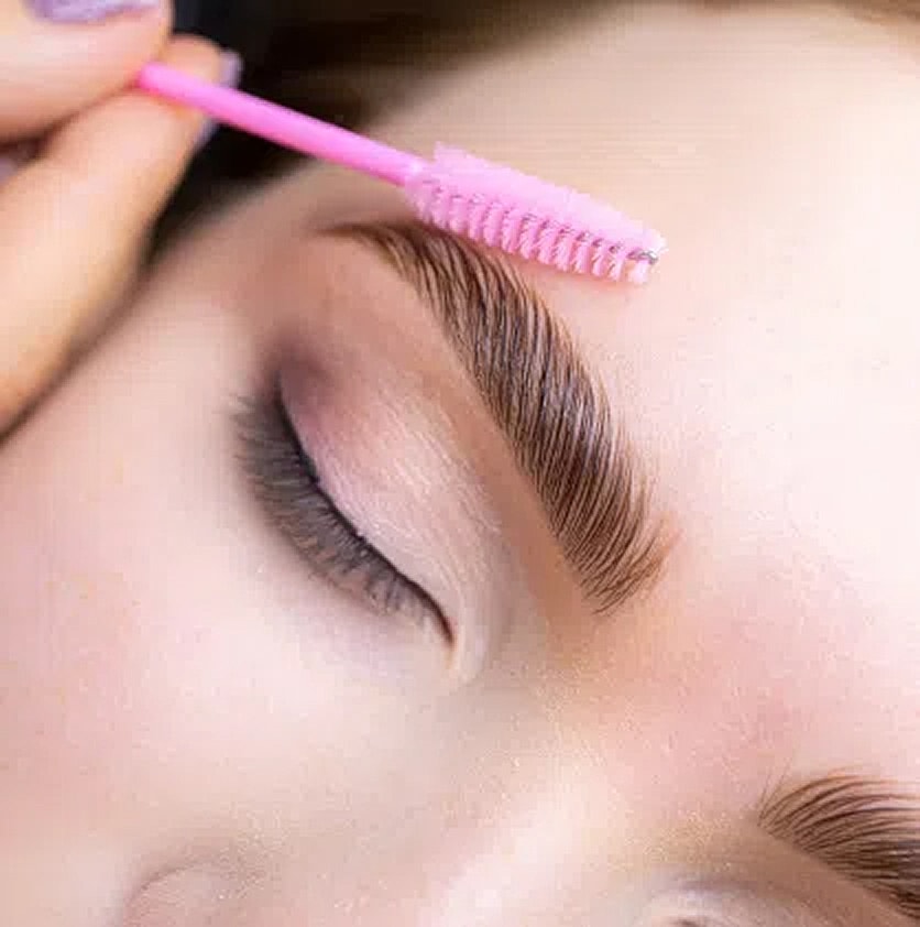 Applying brow gel with a pink brush.