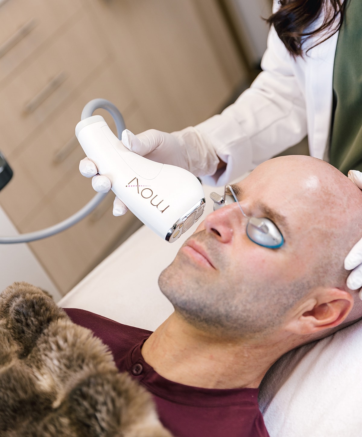 Man receiving skincare treatment with Moxi device.