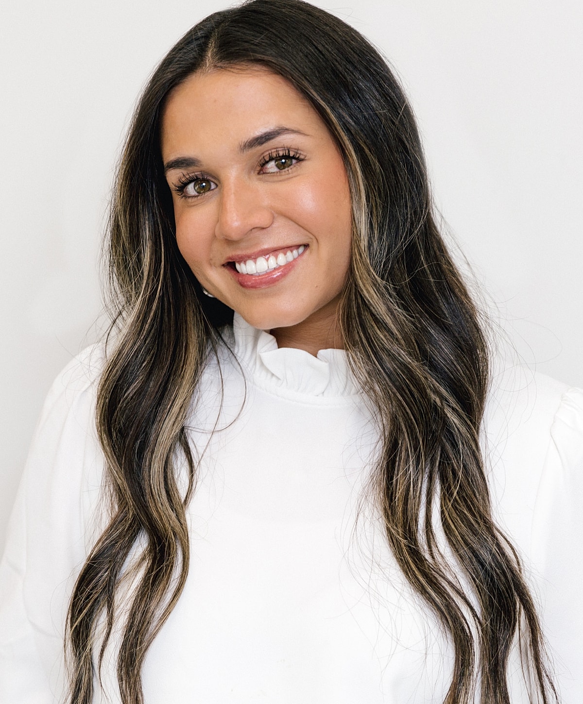 Smiling woman with long hair in white outfit.