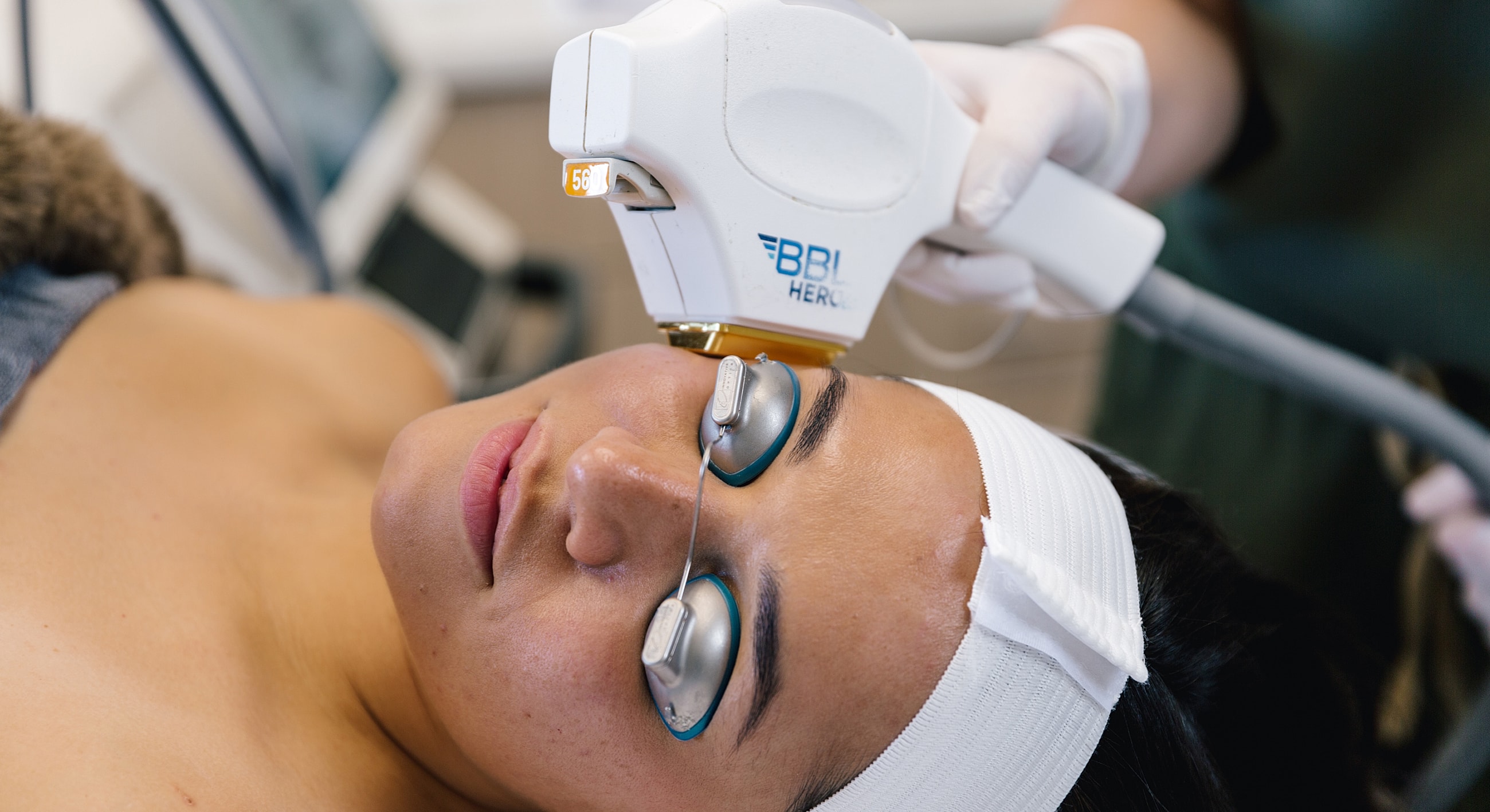 Woman receiving facial treatment with laser device.